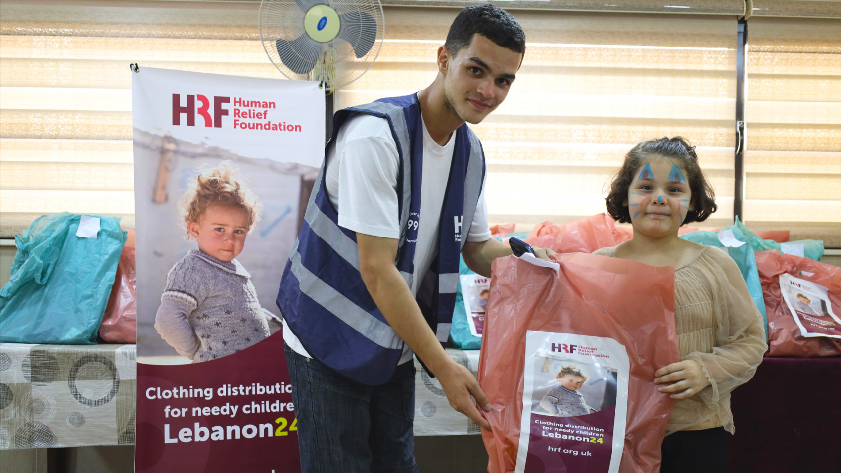 A HRF representative presenting clothes to a young Lebanese girl.