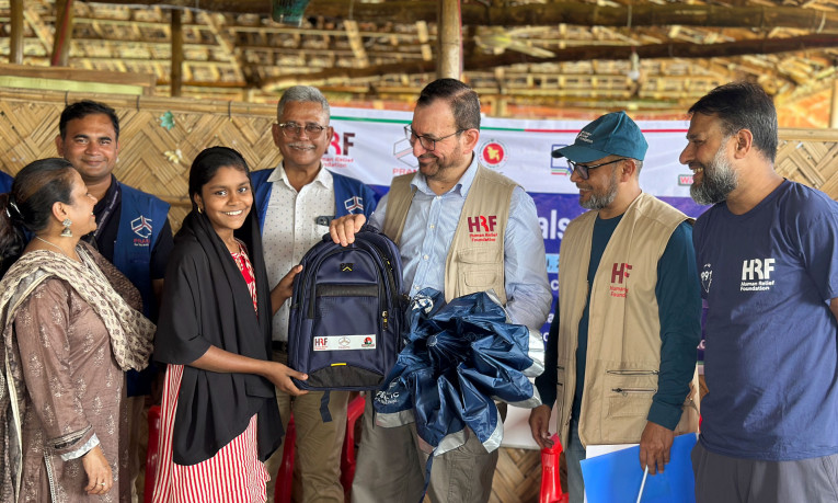 HRF CEO Dr Nabeel Al Ramadhani presents a new bag to a Rohingya refugee child