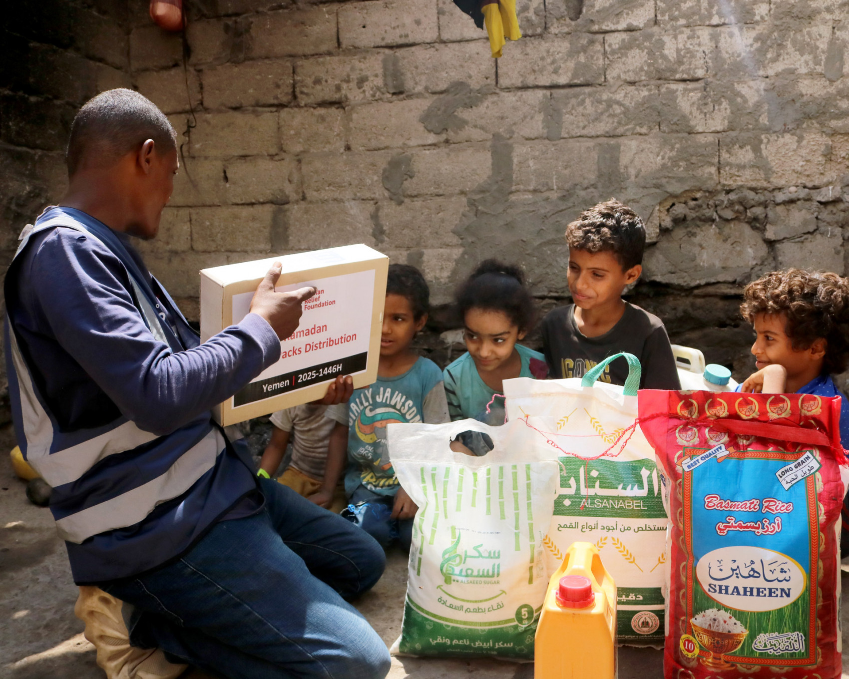 Children in Aden, Yemen receiving a Ramadan food pack from a Human Relief Foundation aid worker.